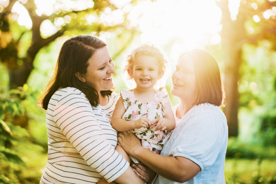 two mothers hold their daughter during their family portrait session at Hampton Park in downtown Charleston, SC