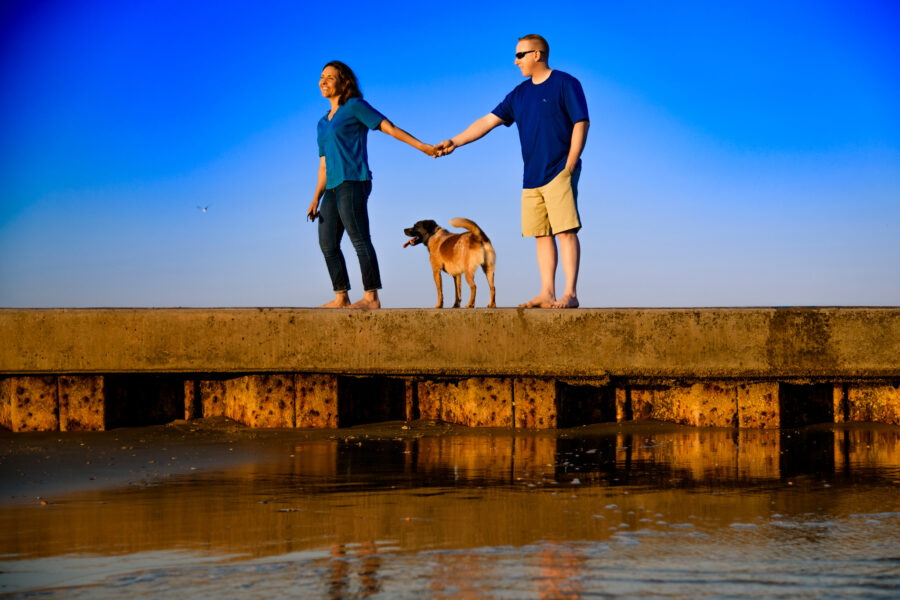 Couple with dog on pier on Folly Beach - Chrisman Studios