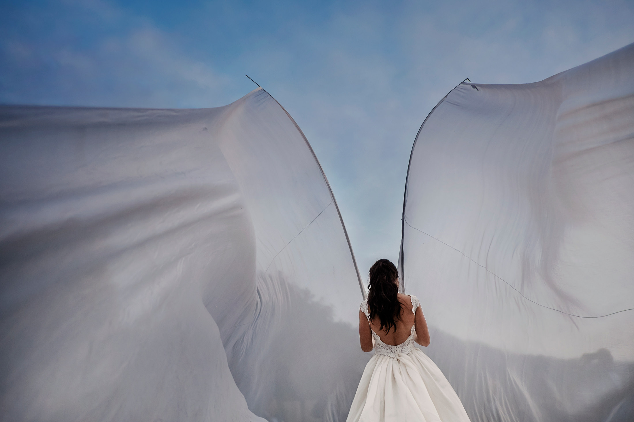 A bride wears decorative wings at her destination wedding in Lake Como, Italy.